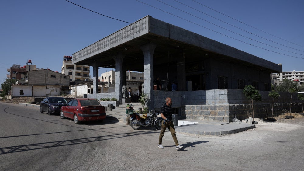 A person walks past the Al-Radwan guest house, where a deadly shooting occurred, in the predominantly Druze city of Sweida, Syria, July 25, 2025. 