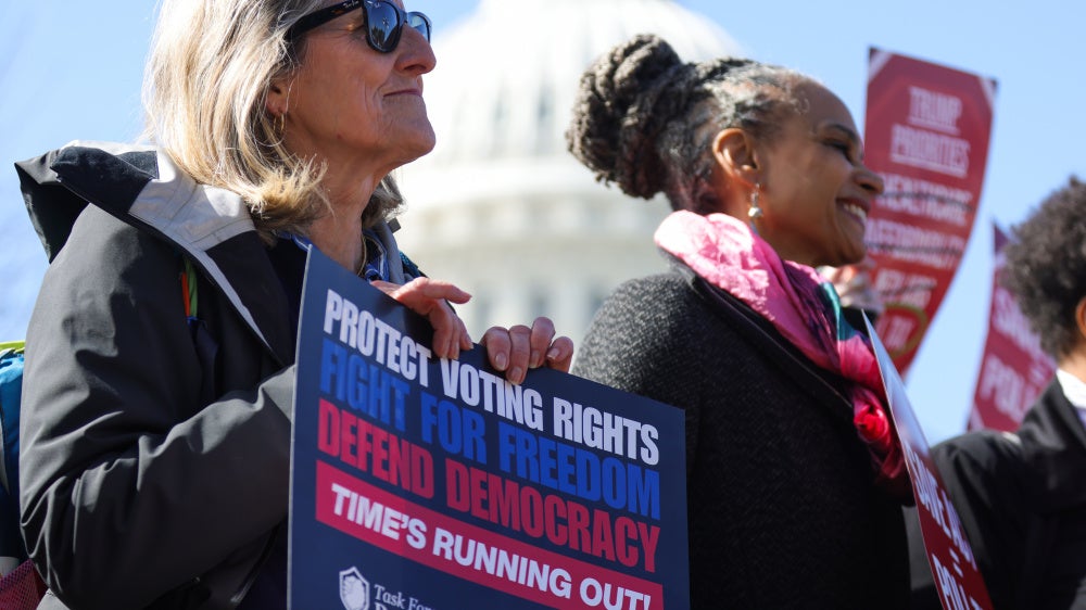People hold signs at a rally and press conference against the SAVE America Act at the US Capitol in Washington, DC, on March 18, 2026.