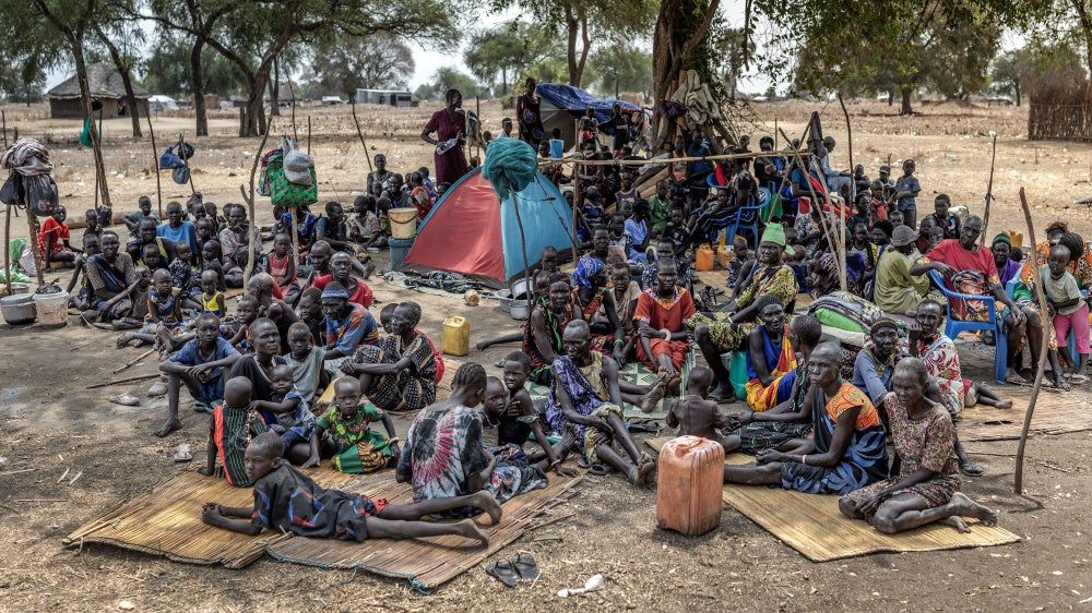 Families gather under a tree at an informal site where displaced people, many from neighboring Jongeli state, have assembled without assistance or shelter at Yolakot informal camp near Mingkaman, Lakes state on February 14, 2026. 