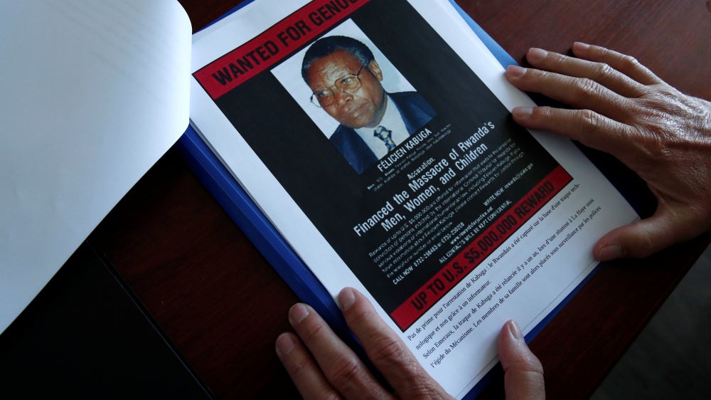 The head of the Gendarmerie’s Central Office for Combating Crimes Against Humanity, Genocides and War Crimes (OCLCH), displays documents with a wanted poster of Félicien Kabuga, May 19, 2020.