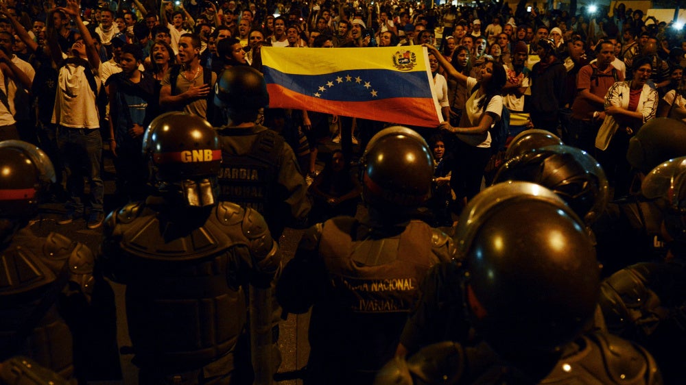 Anti-government students show a national flag to a National Guard barricade during a protest in Caracas, Venezuela, on February 16, 2014. 