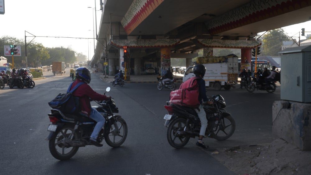 Delivery workers driving through New Delhi, India, 2026.