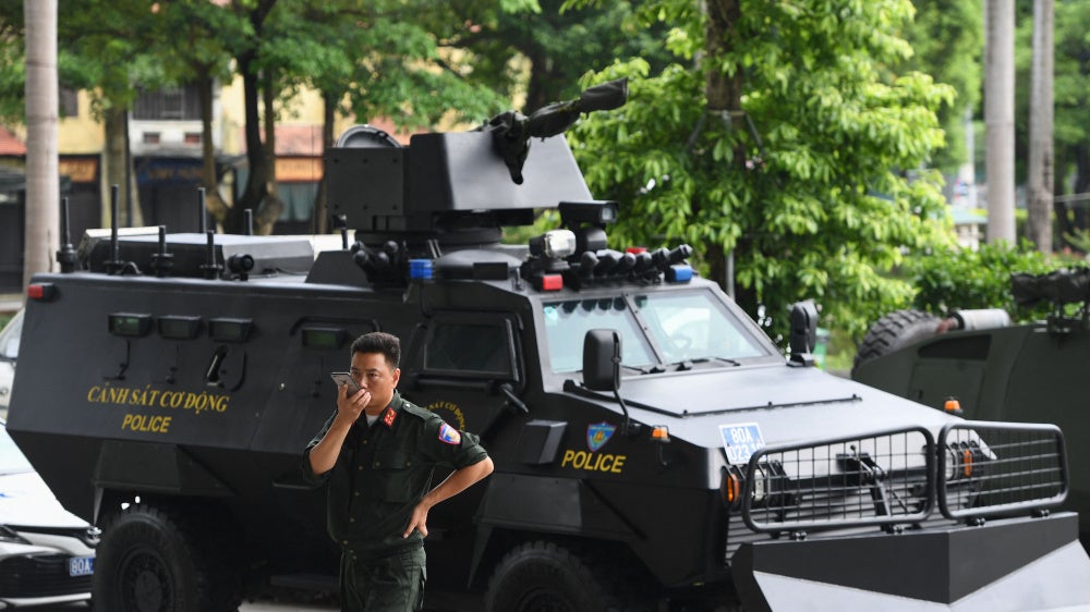 A Vietnamese policeman stands besides an armored vehicle at an exhibition of police equipment in Hanoi, July 20, 2022.