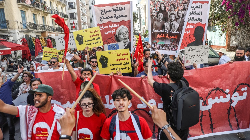 Tunisians hold up placards during a march organized by the Campaign Against the Criminalization of Civil Work to protest racism in Tunis, April 11, 2026