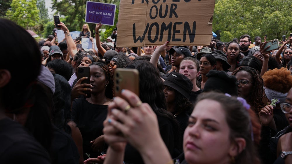 Participants hold signs during a gender-based violence protest at the forecourt of the botanical gardens in Johannesburg, South Africa, November 21, 2025.