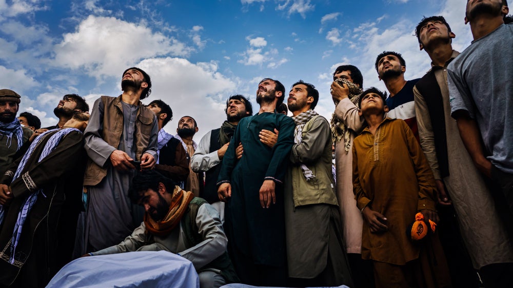 Mourners at a mass funeral for victims of a US drone strike, including seven children, look up as fighter jets circle a cemetery in Kabul
