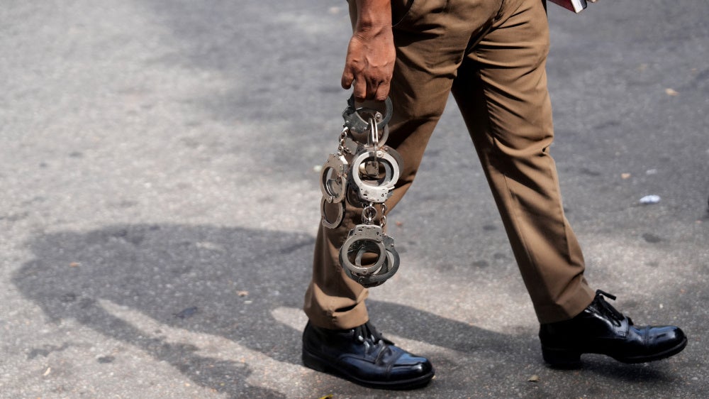 A police officer holds handcuffs as he walks inside a court premises in Colombo, Sri Lanka, August 6, 2026.