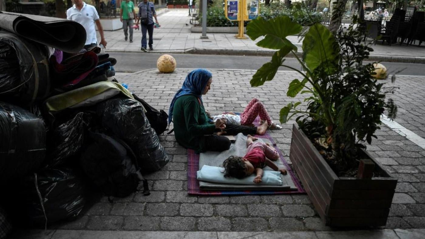 A woman sits with her children in Victoria Square in Athens, Greece, awaiting transfer after being evicted from their place of residence, July 20, 2020.