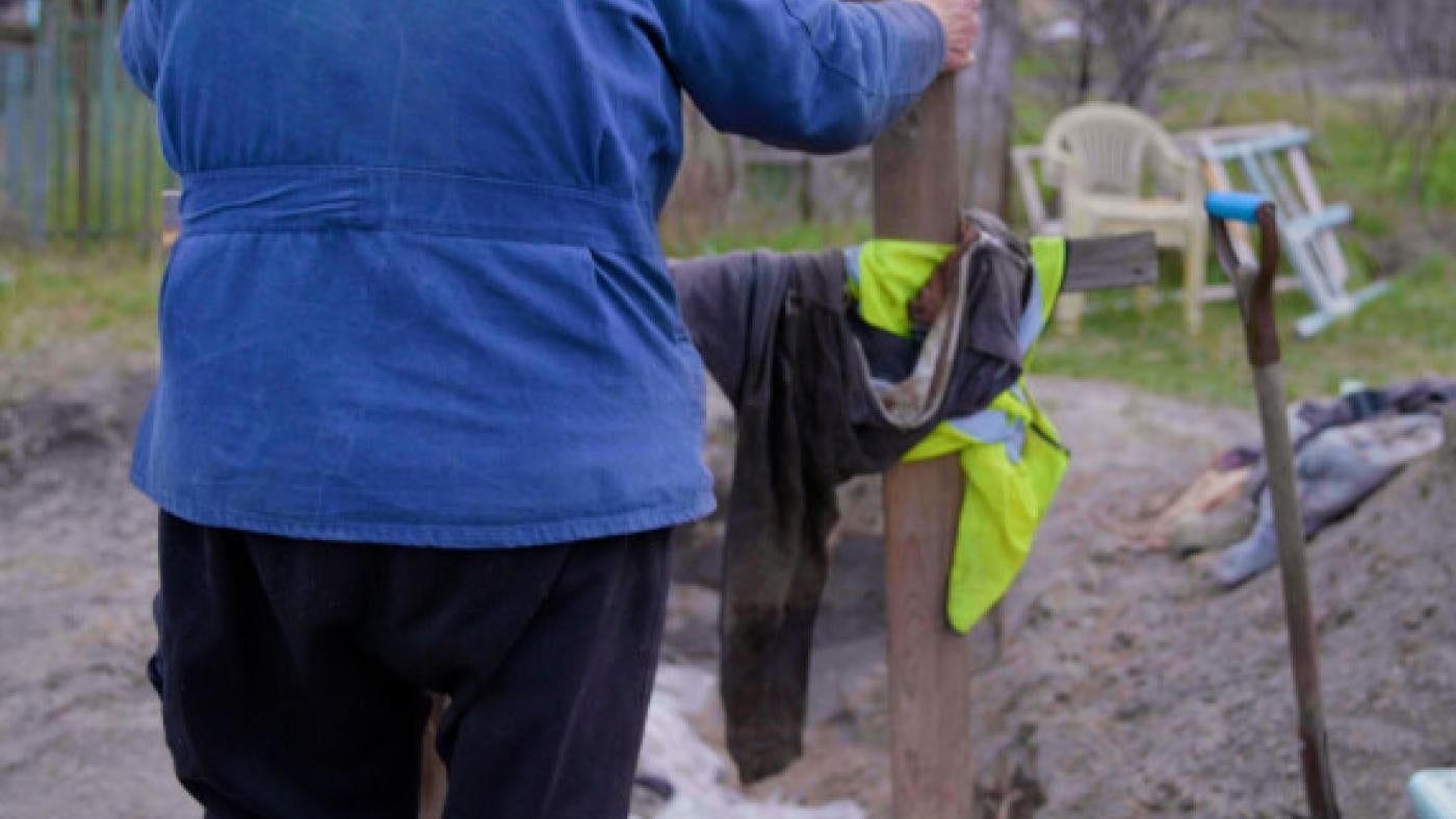 A man puts a cross on a burial site in Ukraine. 