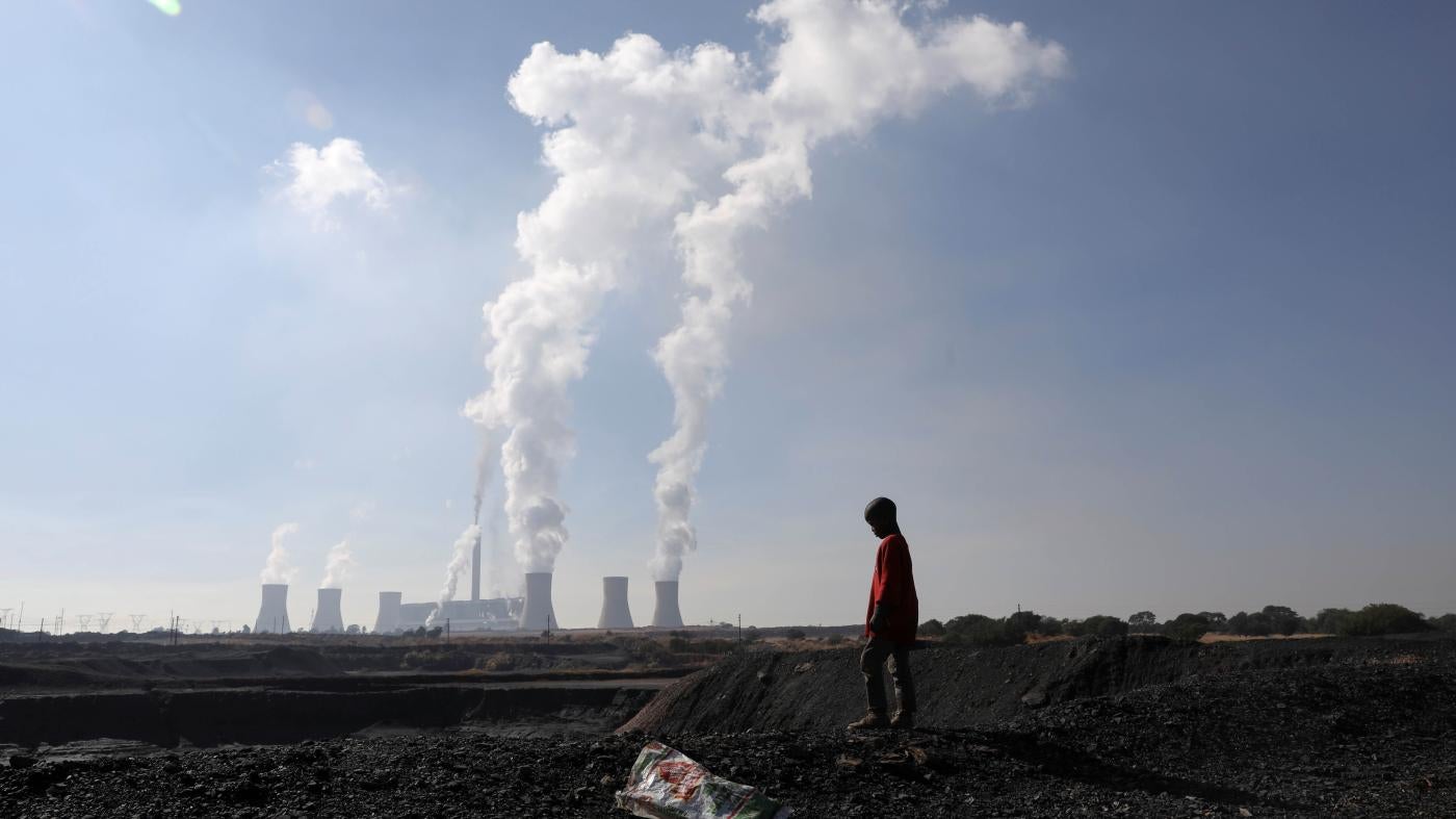  A child near by a coal mine while smoke rises from the Duvha coal-based power station owned by the state power utility Eskom, in Emalahleni, Mpumalanga province, South Africa, June 2, 2021.
 © 2021 Siphiwe Sibeko/Reuters