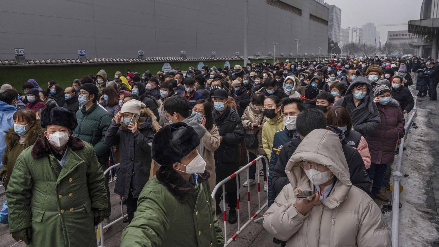 Security personnel stand in front of people lined up for tests to detect Covid-19 at a mass testing site in Beijing, China, January 24, 2022.
 © 2022 Kevin Frayer/Getty Images