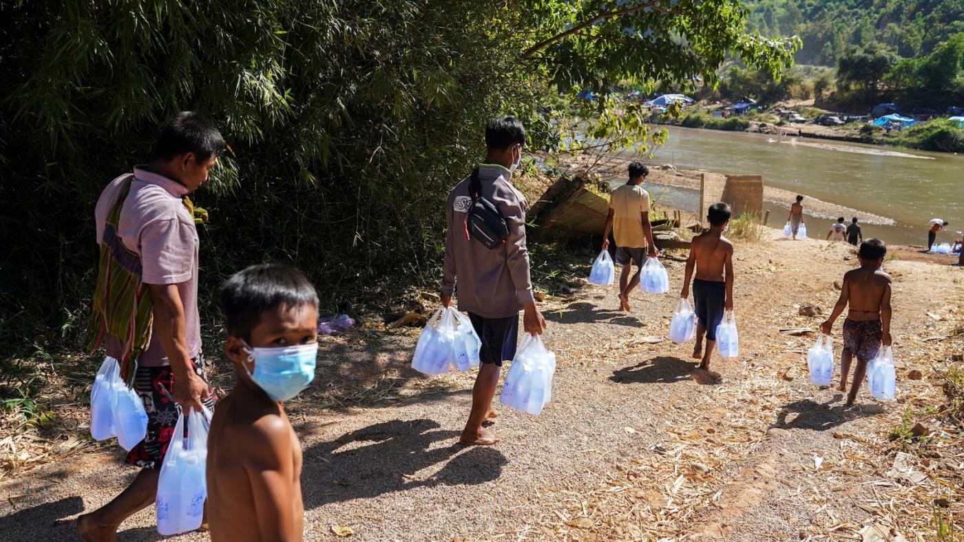  Refugees, who fled fighting between the Myanmar army and non-state armed groups and settled temporarily on the bank of the Moei River, receive aid from Thailand on the Thai-Myanmar border, in Mae Sot, Thailand, January 6, 2022.
 © 2022 Athit Perawongmetha/Reuters