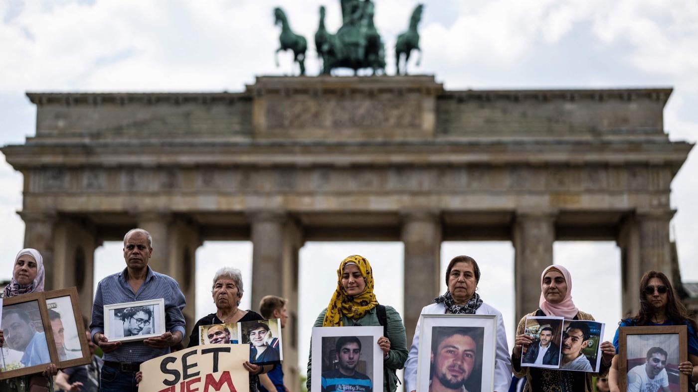  Activistas y familiares de sirios presuntamente detenidos o desaparecidos por la fuerza a manos del gobierno sirio posan con retratos de sirios desaparecidos durante una manifestación frente a la Puerta de Brandemburgo de Berlín el 7 de mayo de 2022.
 © 2022 John MacDougall/AFP/Getty Images