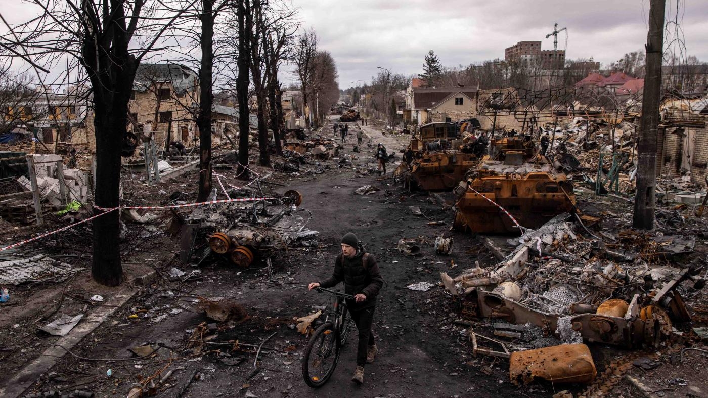  A man pushes his bike through debris and destroyed Russian military vehicles in Bucha, Ukraine, northwest of Kyiv, on April 6, 2022. Human Rights Watch documented numerous &nbsp;apparent war crimes by Russian forces during their occupation of Bucha from March 12-31, 2022.
 © 2022 Chris McGrath/Getty Images 