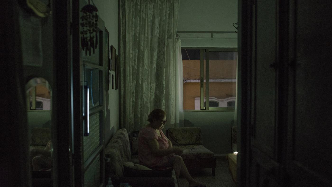  Hasmik Tutunjian usa luzes recarregáveis em sua sala de estar durante cortes de energia em Beirute, Líbano, 26 de agosto de 2022.
 © 2022 Laura Boushnak/The New York Times/Redux