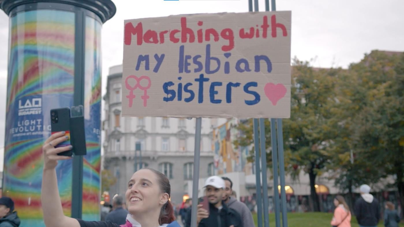 A woman holds a protest sign that says "Marching with my lesbian sisters"
