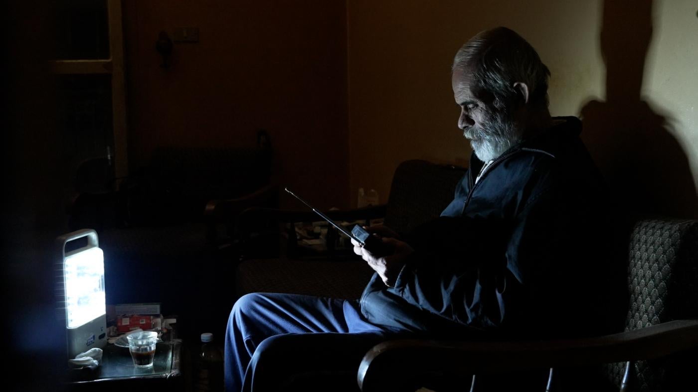 Khodor Al Haushi listens to his battery operated radio in his dark apartment in Beirut, Lebanon. 