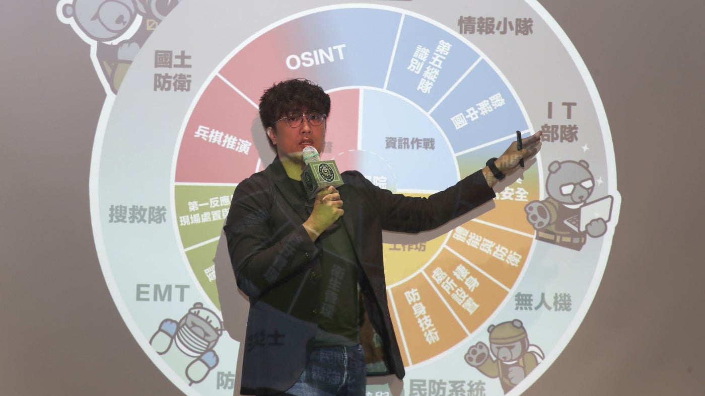 Puma Shen stands in front of a projected slide