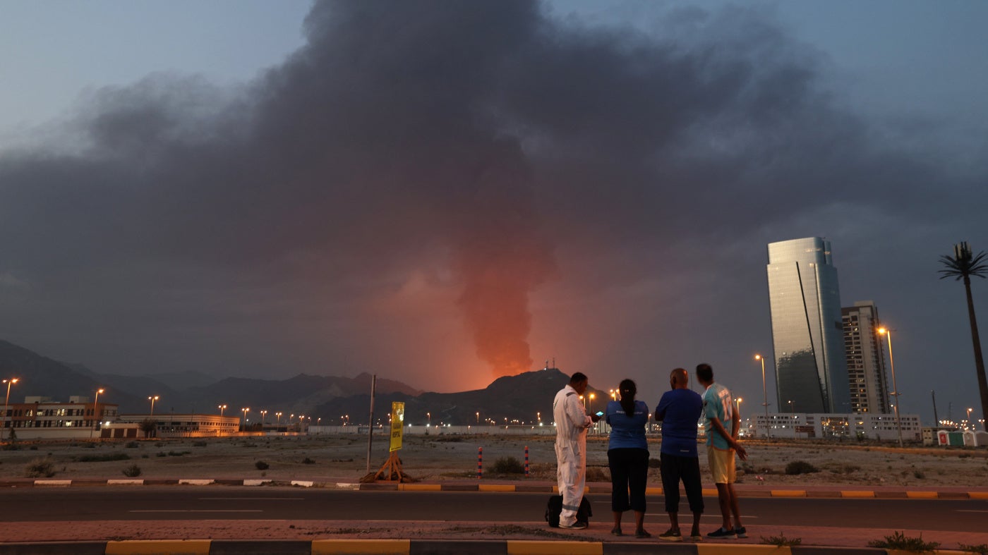 Foreign workers watch a plume of black smoke following an explosion in the Fujairah industrial zone in the United Arab Emirates, March 3, 2026. 