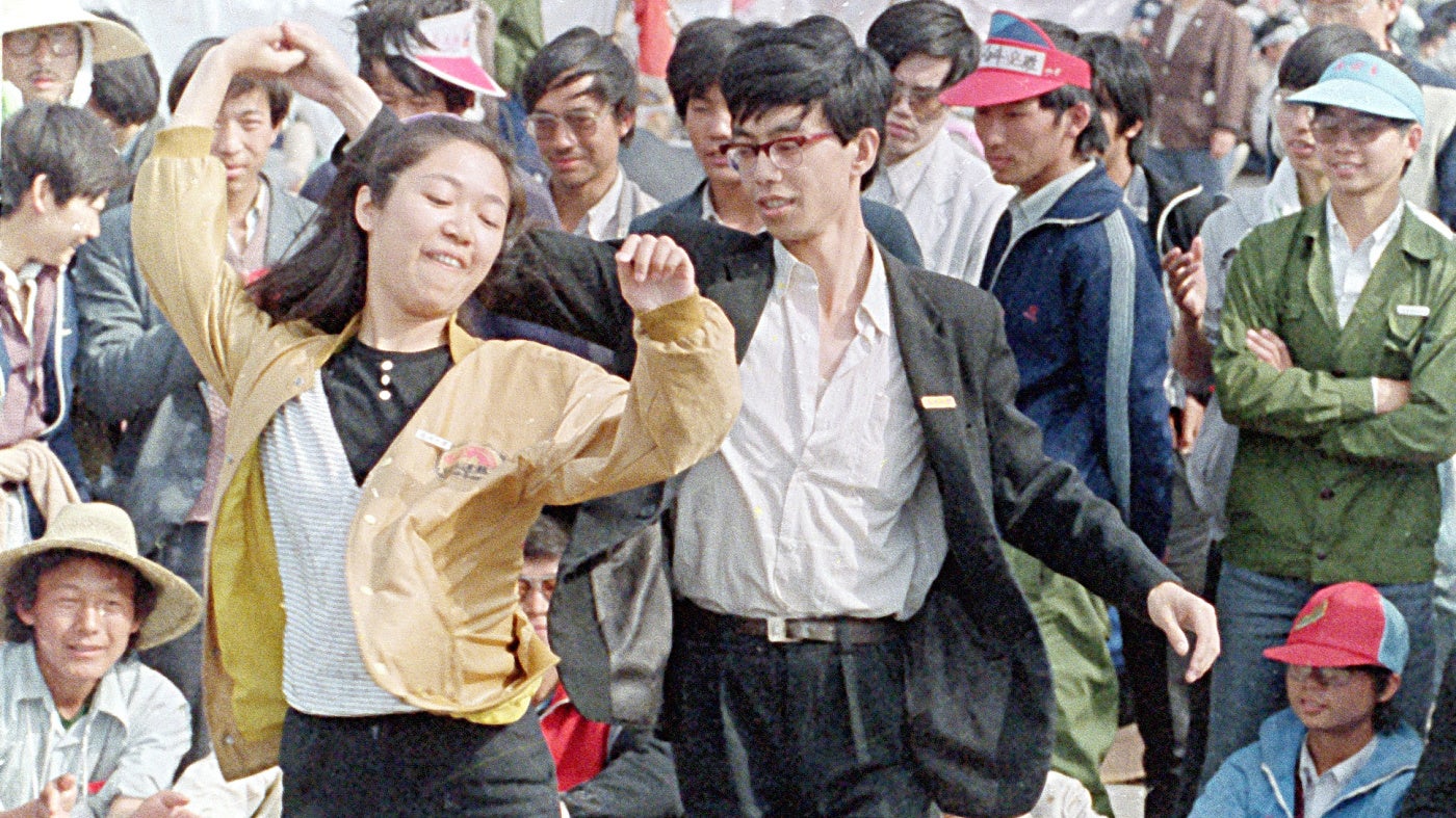 University students dance during the pro-democracy demonstration in Tiananmen Square on May 22, 1989, in Beijing, China. 
