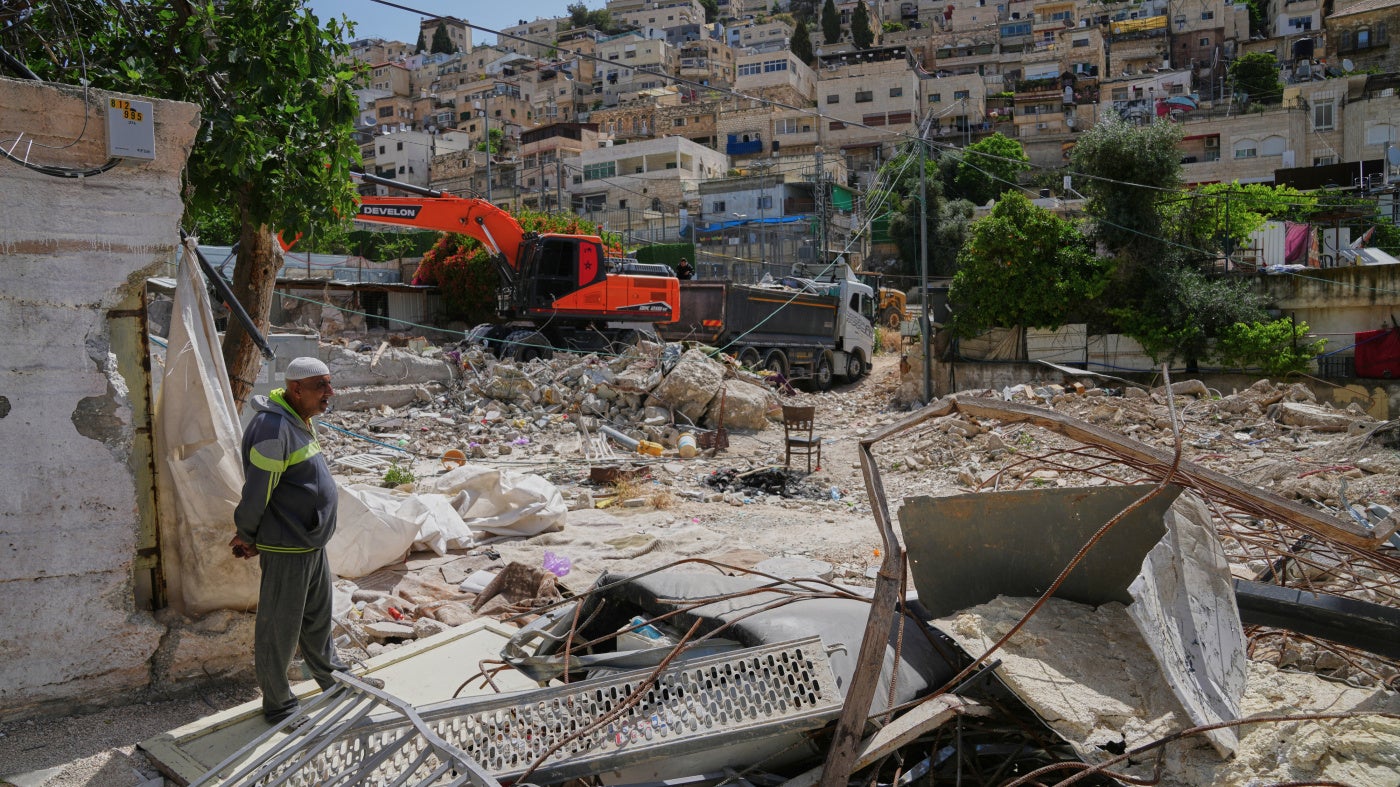 A Palestinian man looks on as an excavator clears the rubble of homes demolished by Israeli authorities in the Silwan neighborhood of east Jerusalem, May 19, 2026.