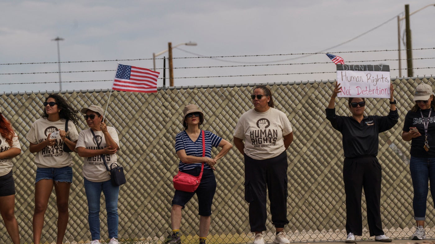 Protesters opposing mass deportations by ICE hold signs during a demonstration held outside of Fort Bliss