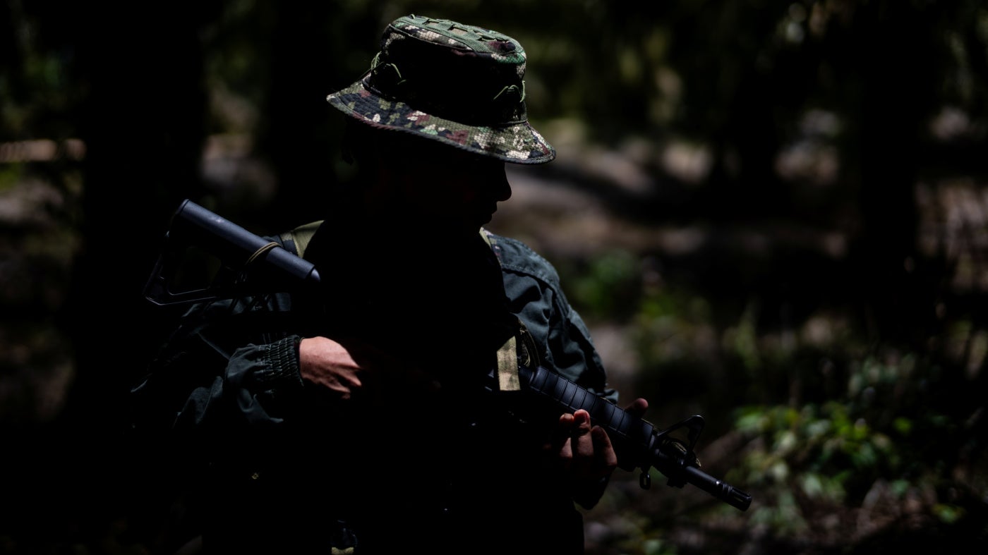 An unidentifiable child soldier holding a gun