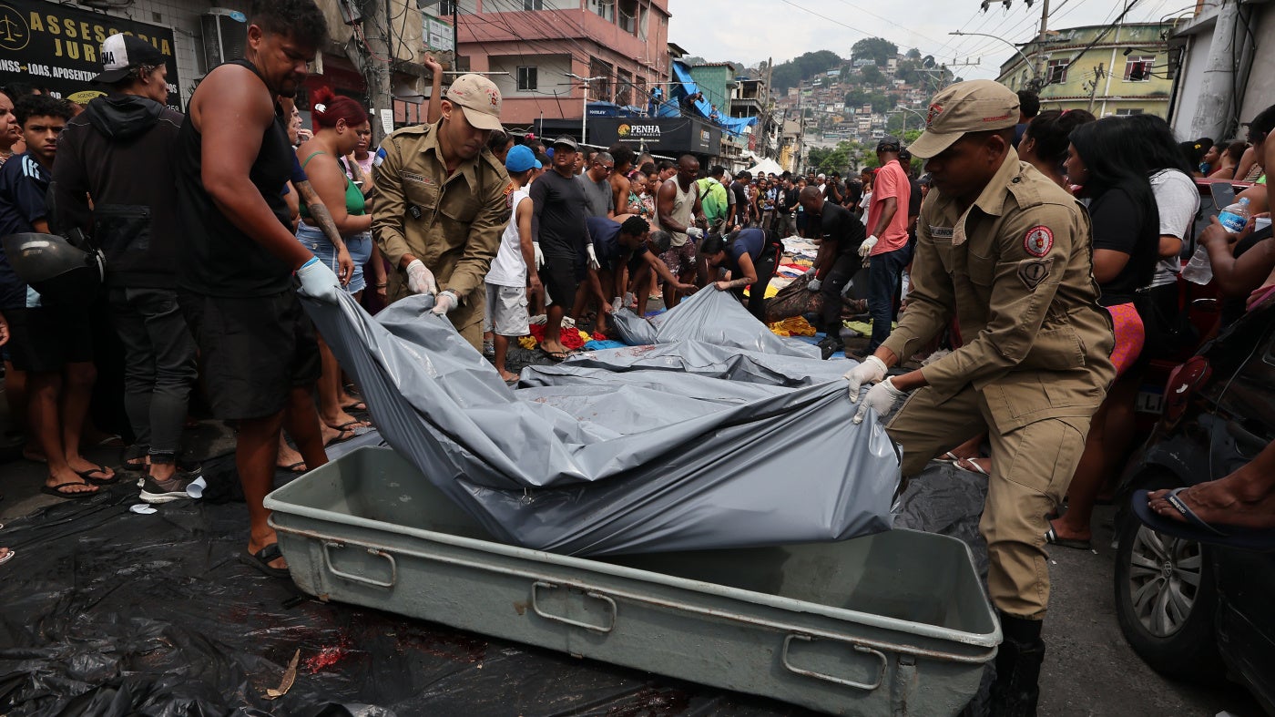 Firemen lift bodies recovered from the nearby forest in Saint Luke Square in Complexo da Penha