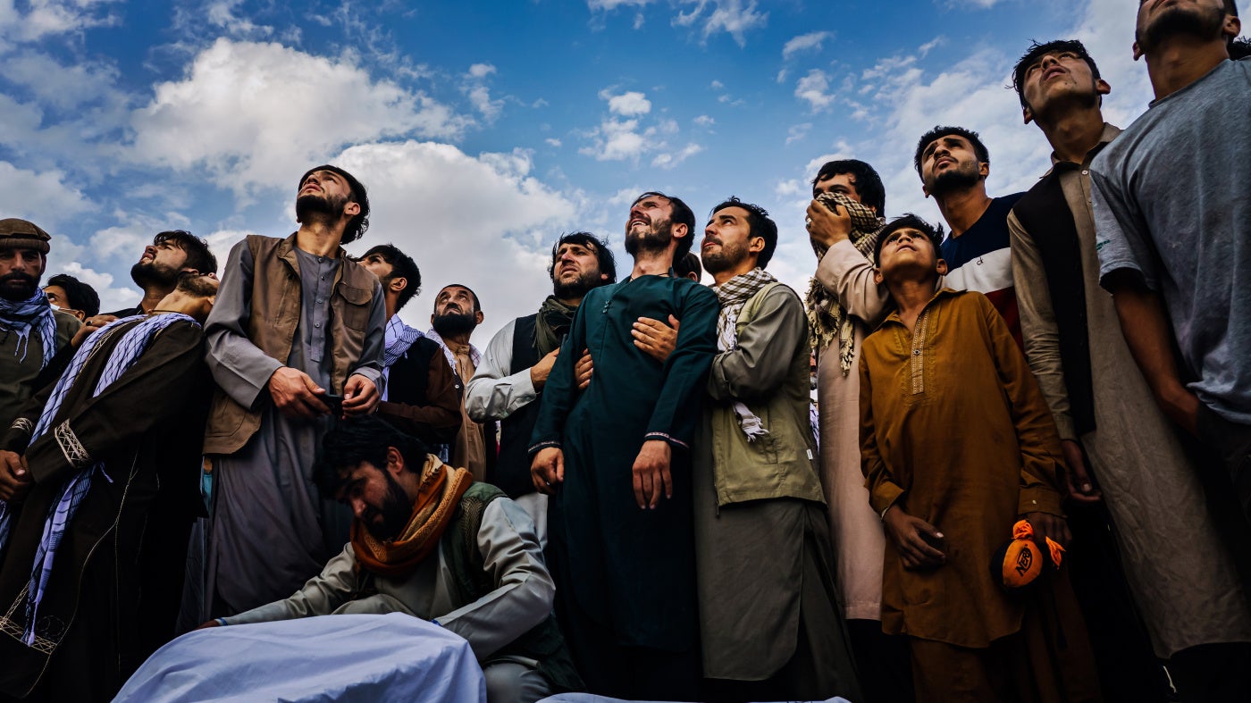 Mourners at a mass funeral for victims of a US drone strike, including seven children, look up as fighter jets circle a cemetery in Kabul