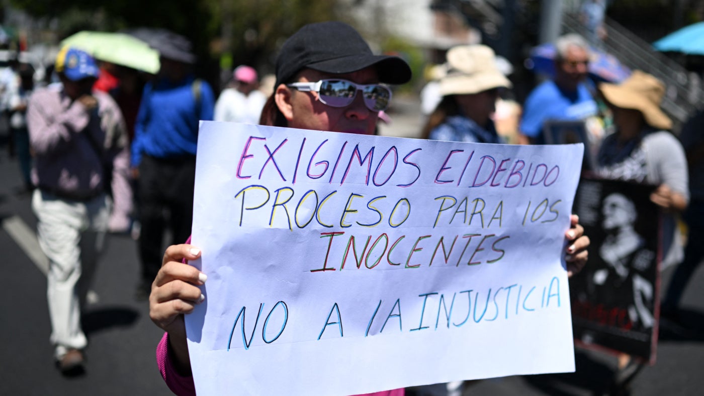 A woman holds a sign reading "We demand due process for the innocent. No to injustice" during a protest 