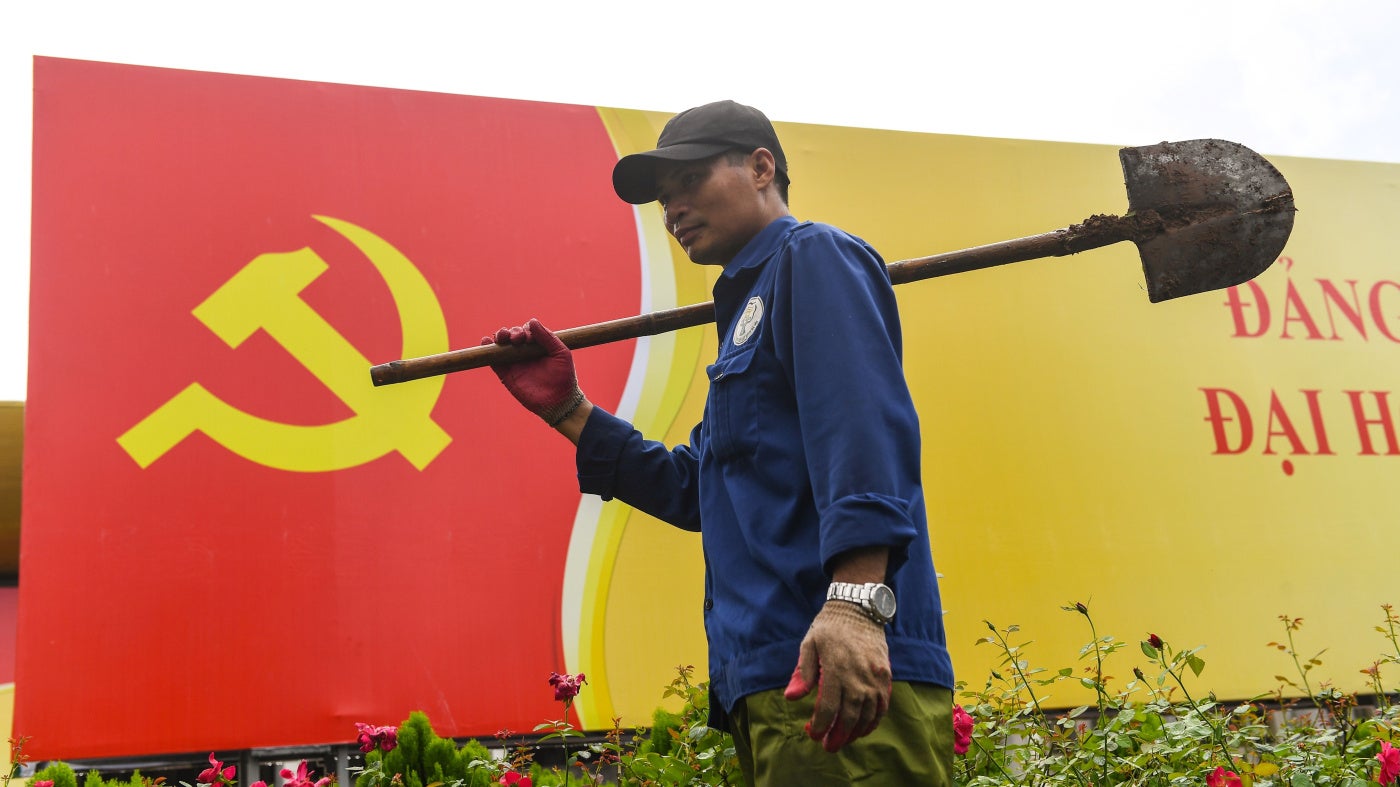 A worker walks past a sign with the Vietnamese Communist Party flag in Hanoi