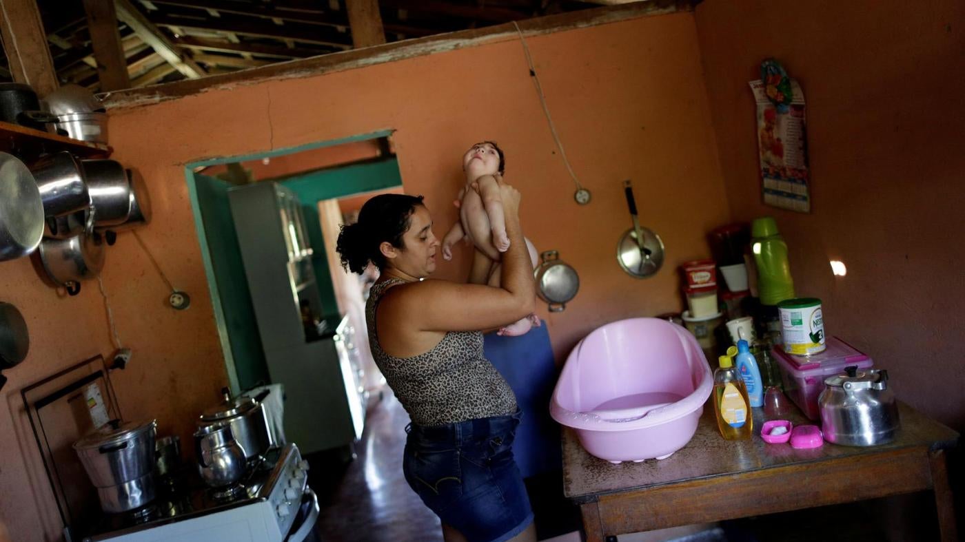 Raquel bathes her daughter Heloisa, a girl with Zika syndrome born in April 2016. Raquel says she cannot afford the medicines her twin daughters need for convulsions. 