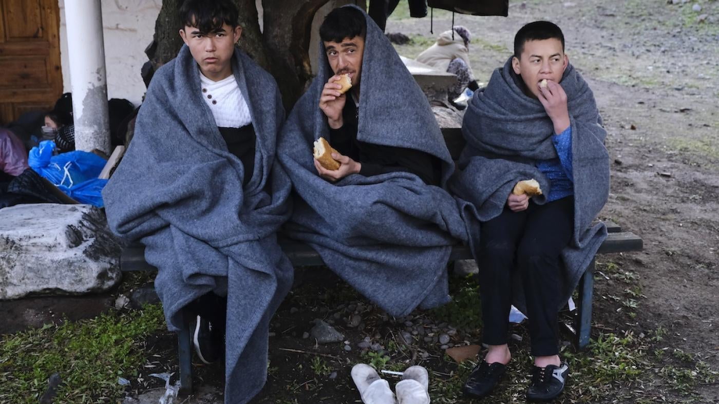 Migrants who arrived yesterday to Greece from Turkey eat bread as they try to warm themselves at the village of Skala Sikaminias, on the Greek island of Lesbos on Friday, March 6, 2020. 