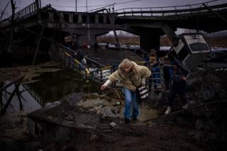 People flee across a destroyed bridge on the outskirts of Kyiv, Ukraine, March 2, 2022.
