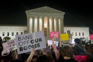 People protest holding signs outside of the US Supreme Court at night