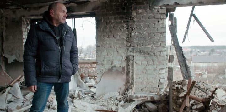 Mykhailo Yatsentiuk in the ruins of the building at 2 Pershotravneva Street in Izium, his former home, in December 2022