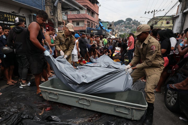 Firemen lift bodies recovered from the nearby forest in Saint Luke Square in Complexo da Penha