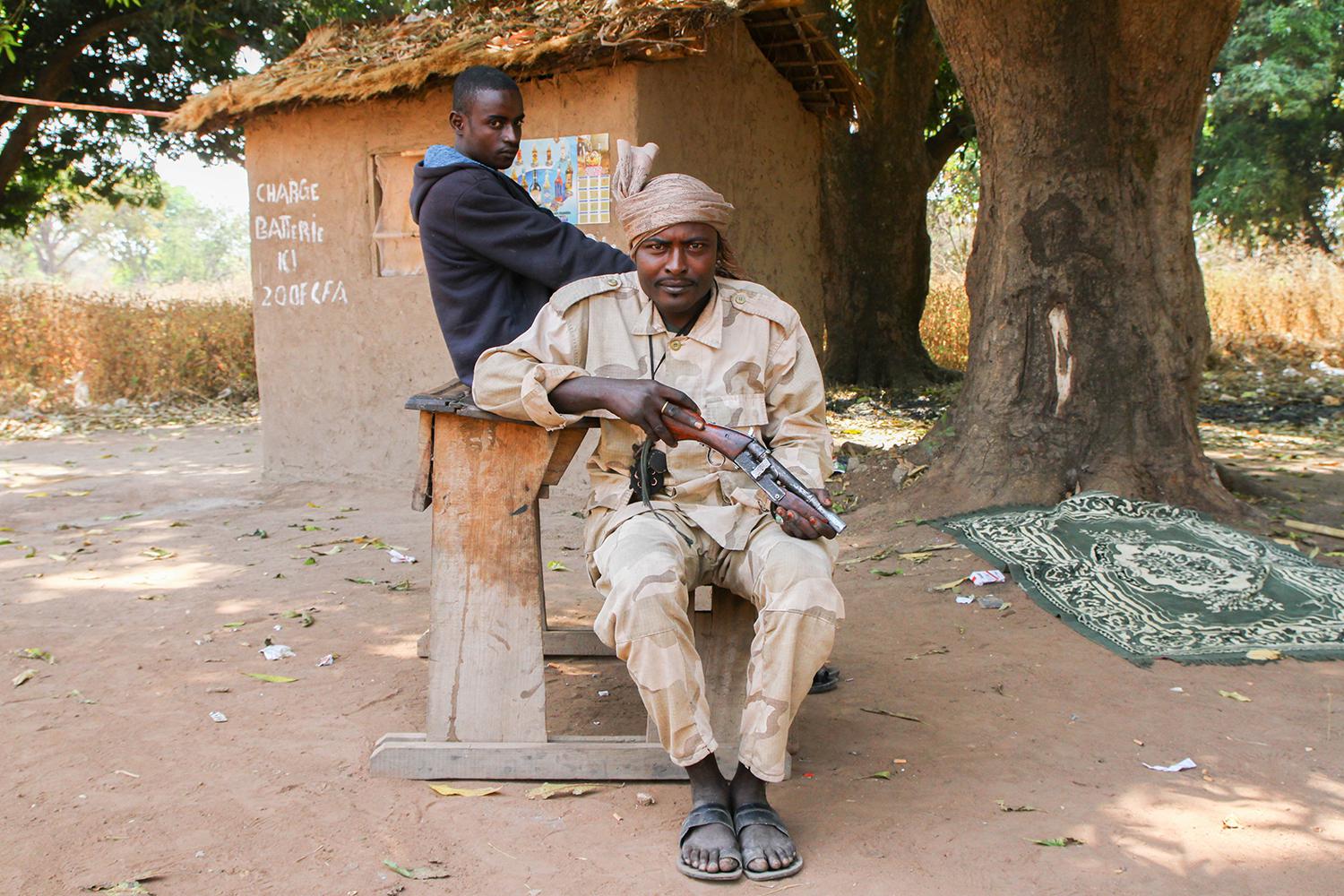 Deux miliciens du Mouvement Patriotique pour la Centrafrique (MPC), un groupe armé issu de la Séléka, à un poste de contrôle routier à Bojomo, dans la province d'Ouham, avec un pupitre qu'ils ont saisi dans l'école de la ville.