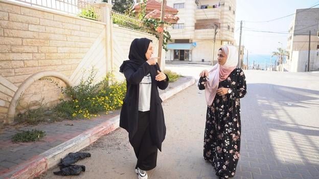 26-year-old Heba AbuJazer (left) and her 25-year-old sister Eman (right), who have hearing disabilities, communicate using sign language in Gaza.&nbsp;