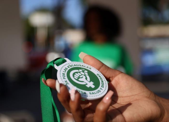 An abortion rights activist holds a plastic medallion reading "For the #3Causales (#3LegalGrounds), Life, Health and Dignity" during a protest to urge parliament to approve a proposed reform to the penal code that could end the total ban on abortion, in Santo Domingo, Dominican Republic March 18, 2021.&nbsp;