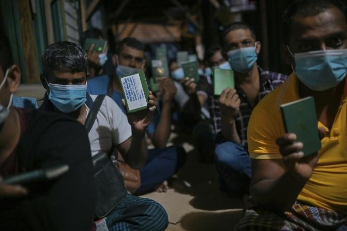 Migrant workers show their passport during a raid in Dengkil, outside Kuala Lumpur, Malaysia on&nbsp;June 21, 2021.