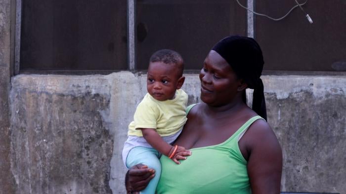 A woman holding a baby poses for the camera