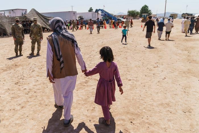 A man walks with a child through Do&ntilde;a Ana Village in Fort Bliss, where Afghan refugees are being housed, in New Mexico on September 10, 2021.