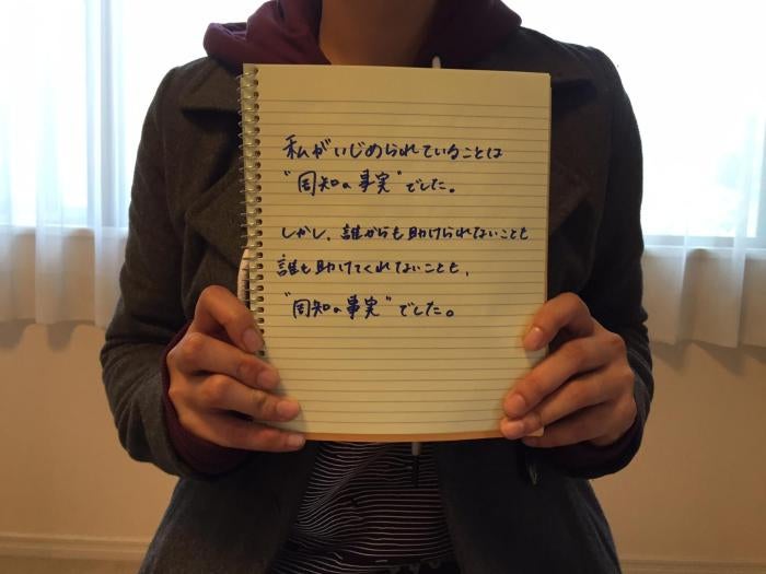 A 20-year-old Japanese woman who was bullied by her classmates in junior high school holds a notebook displaying the message: &ldquo;It was common knowledge that I was being bullied. It was also common knowledge that my teachers would never help me.&rdquo; 