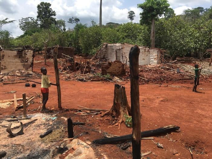 Children stand among houses burnt during an eviction operation in the protected forest of Goin-D&eacute;b&eacute;, C&ocirc;te d'Ivoire, in January 2016.
