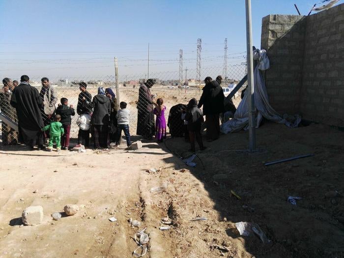 Residents of Shahama camp speak with relatives through the camp fence. 