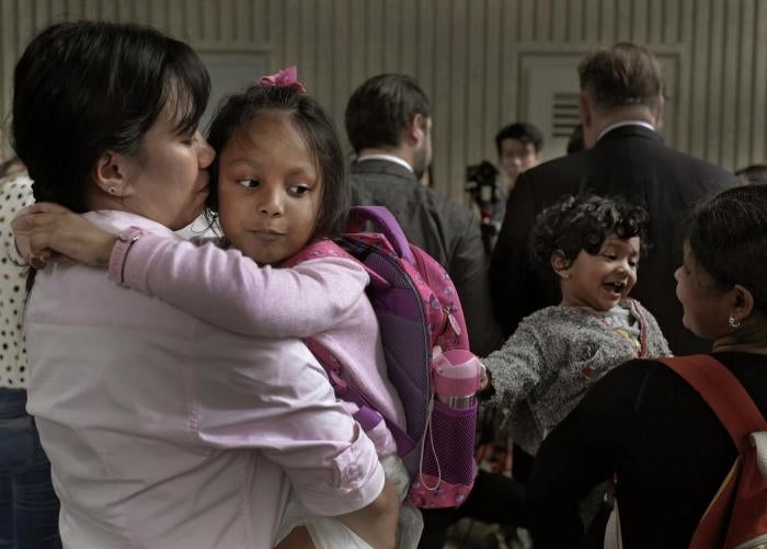 Two mothers hold their children in their arms as they wait outside the immigration department's building in Hong Kong, China.