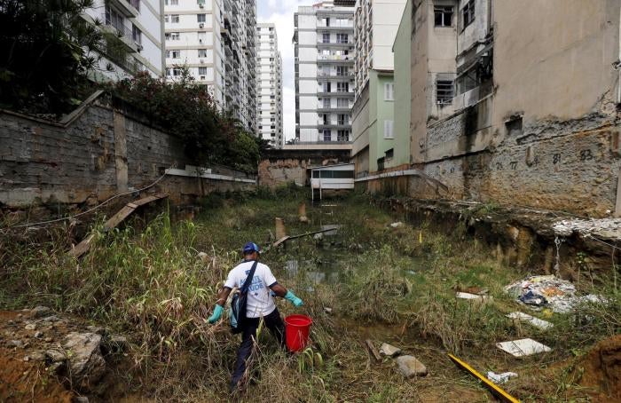 A health agent carries a bucket of guppy fish to place them in standing water to consume larva of Zika-transmitting mosquitoes in an empty lot of Rio de Janeiro's Tijuca neighborhood, Brazil, February 17, 2016. 