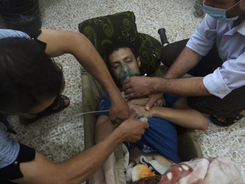 Des secouristes aident un homme à respirer à travers un masque à oxygène, suite à une attaque chimique présumée à Jesreen, dans la banlieue de Damas (Syrie), le 21 août 2013.