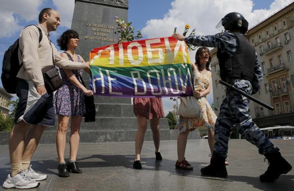 Участники митинга в поддержку прав ЛГБТ-сообщества держат радужный флаг в то время, как сотрудник полиции пытается их остановить. Центр Москвы, 30 мая 2015 г. 
